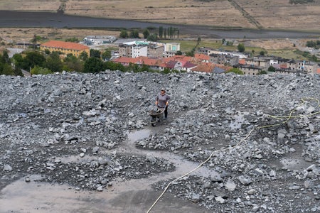 Wide-angle view of person pushing wheelbarrow through chromium mine